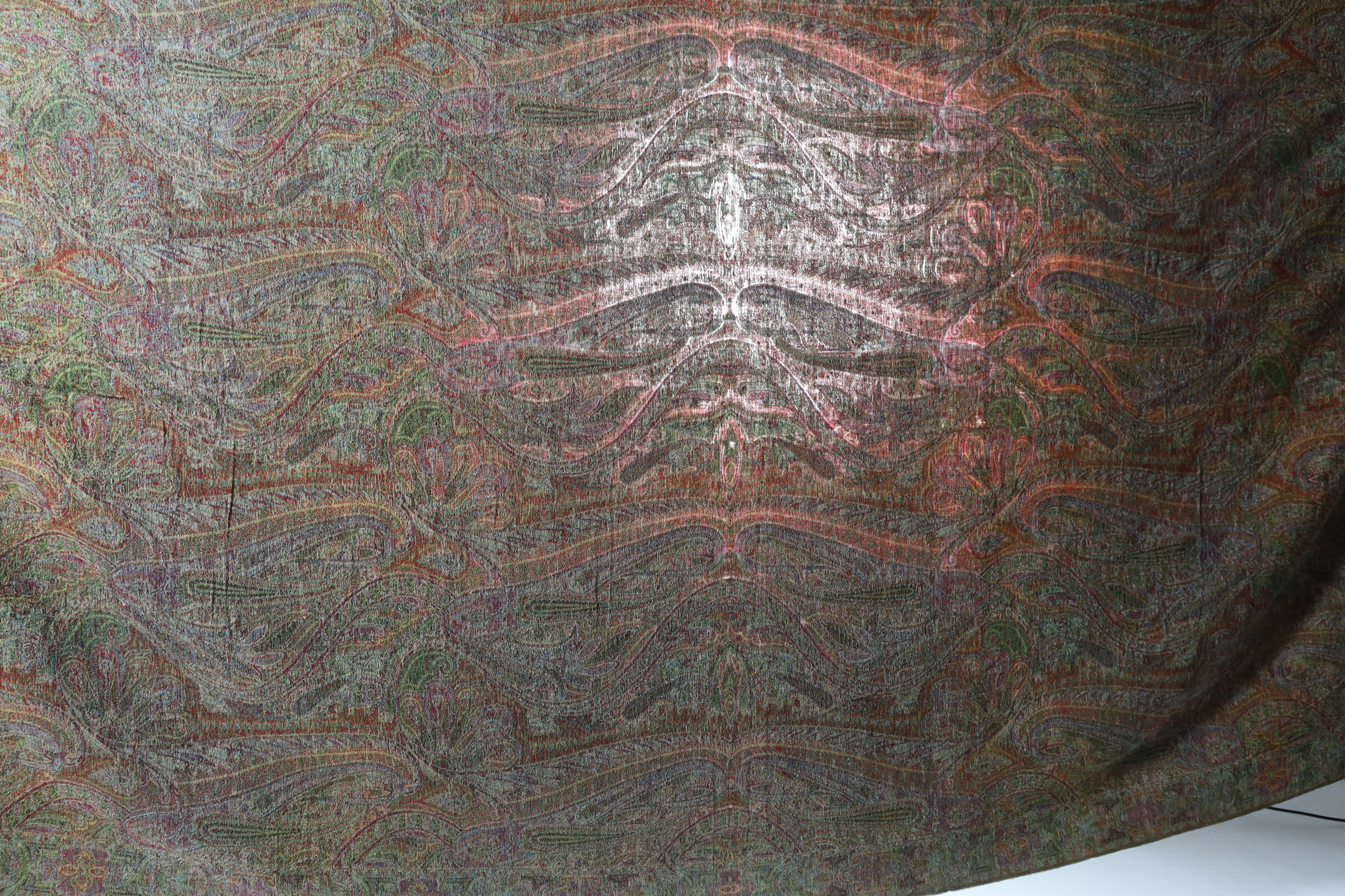 An 1860’s-70’s Scottish Paisley wool shawl, woven with multi coloured wools in a large scrolling teardrop design, bordered and fringed both ends 165cm wide x 345cm long